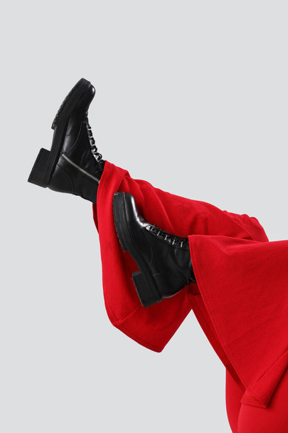 Elegante mujer joven en pantalones rojos y botas sobre fondo claro, primer plano - Foto, Imagen