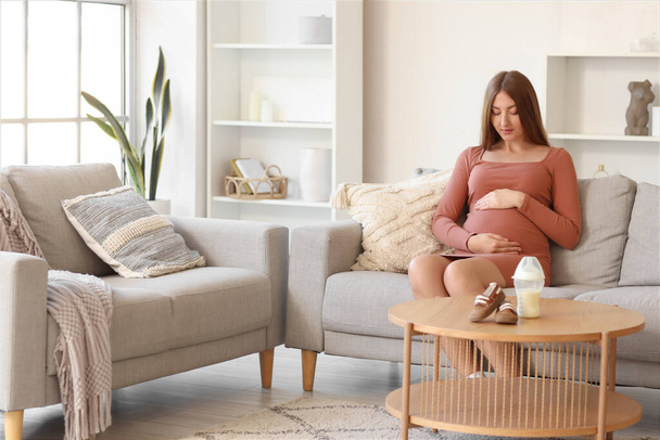 Jeune femme enceinte reposant sur un canapé à la maison - Photo, image