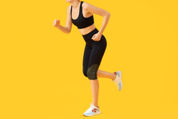 Young woman in black cycling shorts on yellow background - Photo, Image