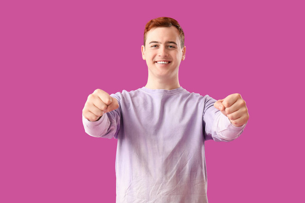 Jongeman met denkbeeldig stuurwiel op paarse achtergrond - Foto, afbeelding