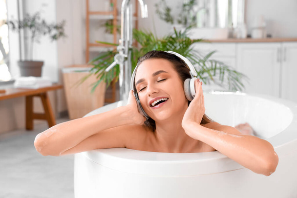 自宅で風呂に入るヘッドフォンの美しい女性 - 写真・画像