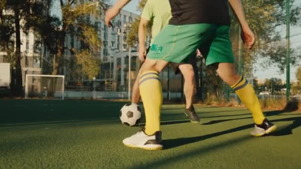 Équipe de sportifs jouant au football sur le terrain de la ville en profitant du temps actif à la campagne. hobby masculin, jeu de sport de compétition - Séquence, vidéo