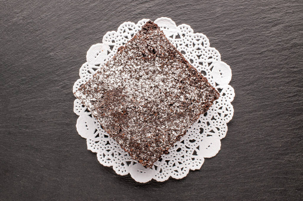 Un morceau de brownie au chocolat classique avec serviette blanche sur pierre d'ardoise, macro, vue du dessus. - Photo, image