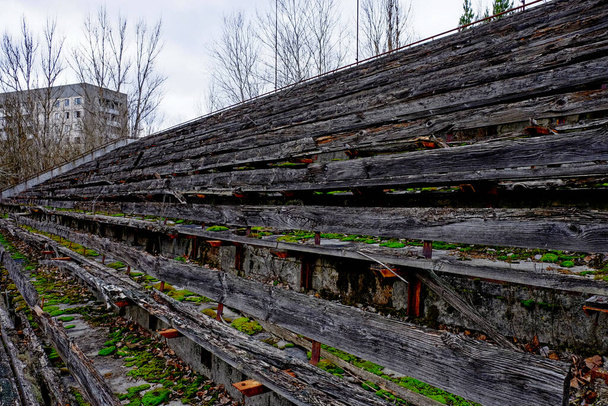 Παλιά ξύλινη σκάλα στην παλιά πόλη Pripyat, Ουκρανία. Οι κερκίδες ενός εγκαταλελειμμένου σταδίου στο Πριπιάτ. Παλιά ξύλινα παγκάκια στο γήπεδο. - Φωτογραφία, εικόνα