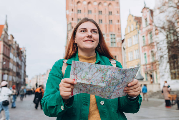 Portrait schöne Frau mit Papierkarte auf der städtischen Straße. Glückliche Touristen reisen durch Europa. Urlaubskonzept durch die Erkundung interessanter Reiseziele. 30er-Jahre-Frau sucht Orte - Foto, Bild