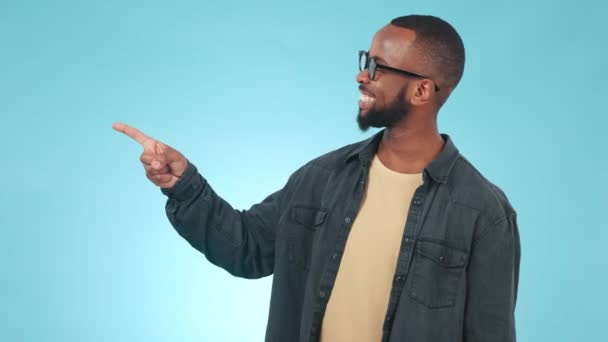 Pointing, choice and face of black man in studio with mockup space for options or decision. Choose, select and portrait of young African male model with an ok hand gesture isolated by blue background. - Footage, Video