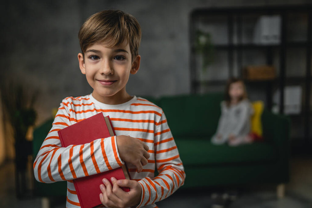 Un garçon enfant caucasien sept ans enfant à la maison écolier portrait tenir livre - Photo, image