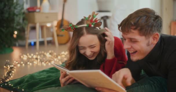 Allegro maschio e femmina amici guardando album di foto insieme a casa durante le vacanze di Natale - Filmati, video