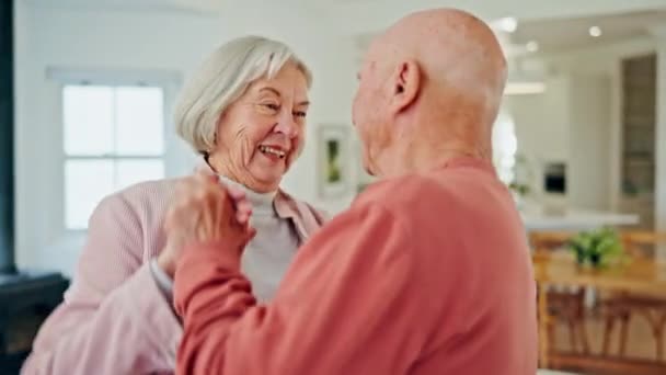 Seniorenpaar, dansen en glimlachen in huis met liefde, romantiek of hechting voor wellness in pensionering. Gelukkig oudere vrouw, oude man en samen in de keuken voor stappen, bewegen en hand in hand houden in huis. - Video