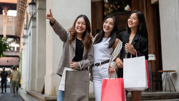 Bir grup eğlenceli, çekici Asyalı genç kız arkadaş yurt dışı gezileri sırasında şehirde alışveriş yapıyorlar. Boş zaman, yaşam tarzı, moda, şehir hayatı. - Fotoğraf, Görsel