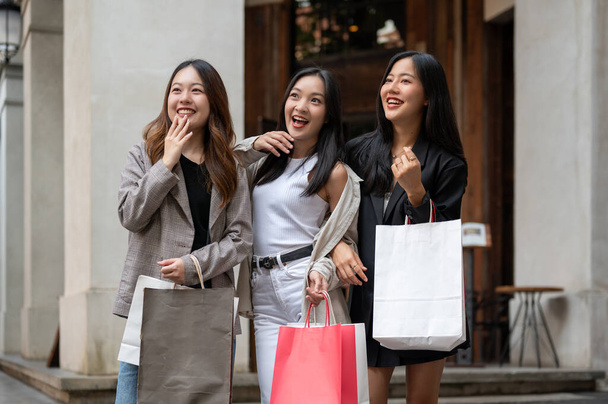 Moda kıyafetleri içinde neşeli ve çekici Asyalı kadınlar şehirde konuşmaktan, gülmekten ve alışveriş yapmaktan keyif alıyorlar. Şehir hayatı, moda, yaşam tarzı, arkadaşlık - Fotoğraf, Görsel