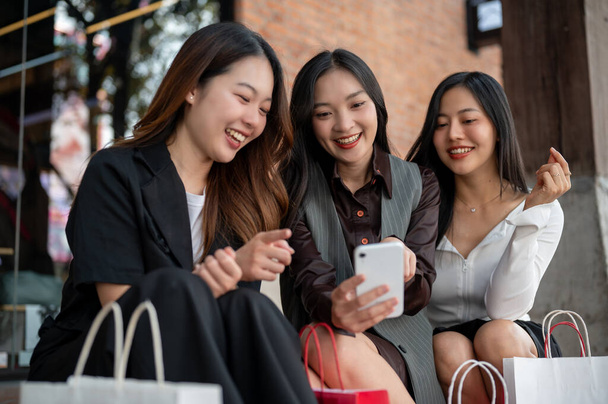 Gruppo di belle ragazze asiatiche felici stanno godendo chit chat mentre riposano sulle scale dopo lo shopping in città insieme. Stile di vita, vita di città, moda - Foto, immagini
