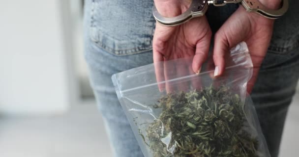 Пакет с марихуаной и арестованная женщина в наручниках. Ответственность за использование и торговлю марихуаной - Кадры, видео