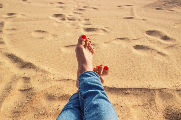 Piernas sobre la arena en la playa
 - Foto, imagen