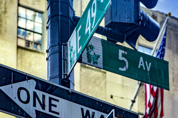 Фотография знаменитого знака Пятой авеню и американского флага, расположенного в самом центре Манхэттена, в самом сердце Большого Яблока в Нью-Йорке, США. - Фото, изображение