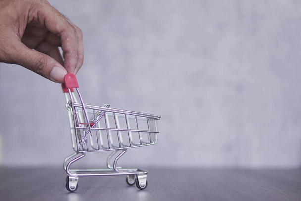 Closeup image of hand push empty shopping cart. Copy space. Business, consumerism and shopping concept - Photo, Image