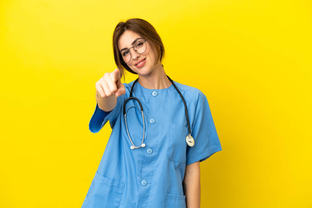Surgeon doctor woman isolated on yellow background points finger at you with a confident expression - Photo, Image
