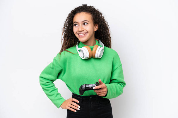 ビデオゲームのコントローラーで遊ぶ若いアラブの女性は,腰と笑顔で腕をポーズホワイトバックで孤立しました - 写真・画像