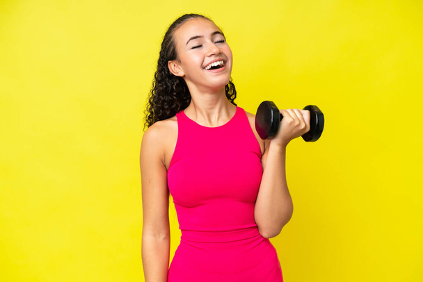 Junge Sportlerin bringt Gewichtheben auf gelbem Hintergrund zum Lachen - Foto, Bild
