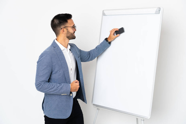 Young caucasian man isolated on white background giving a presentation on white board - Photo, Image