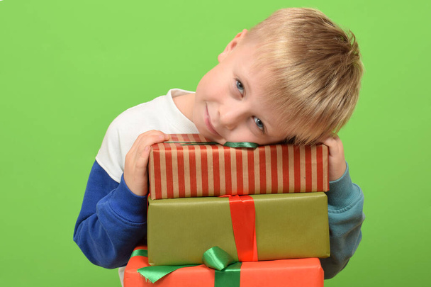 хлопчик з подарунковими коробками на зеленому тлі. Новорічна концепція - Фото, зображення