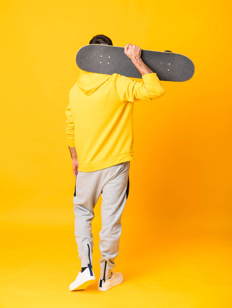 Full-length shot of a skater man over isolated yellow background - Photo, Image