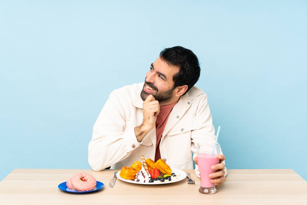 Человек за столом, завтракающий вафлями и молочным коктейлем - Фото, изображение