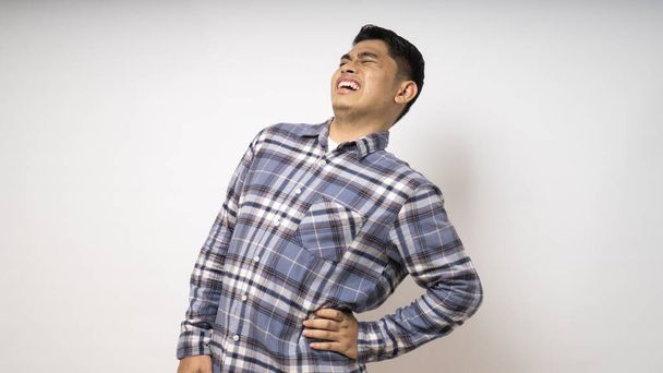 Giovane asiatico uomo indossare camicia soffrire di mal di schiena su sfondo bianco - Foto, immagini