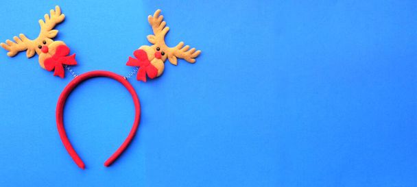 cute Christmas headbands with christmas reindeer horns isolate on a blue backdrop. concept of joyful Christmas party,New year is coming soon, festive season decoration with Christmas elements - Photo, Image
