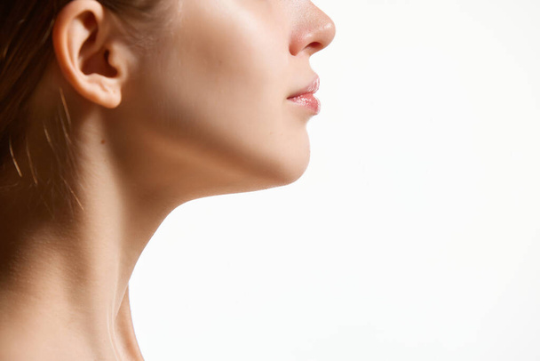 Cropped side view image of female face, neck isolated against white studio background. Reduction of double chin. Concept youth, natural beauty, healthy lifestyle. Negative space for ad - Photo, Image