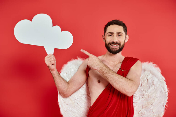 Aşk tanrısı kostümlü neşeli sakallı adam beyaz boş düşünce balonuyla kırmızı üzerinde fikir işareti gösteriyor. - Fotoğraf, Görsel