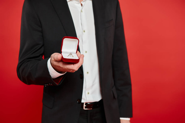 cropped view of successful elegant businessman with ring in jewelry box on red, st valentines gift - Photo, Image