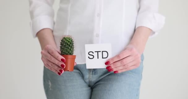 Das Mädchen hält einen Kaktus und ein Blatt Papier, es wird von STD geschrieben. Die Folgen sexuell übertragbarer Krankheiten - Filmmaterial, Video