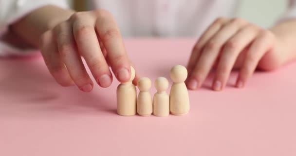 Mãos femininas e bonecas de madeira em um fundo rosa, close-up. O conceito do colapso da família - Filmagem, Vídeo