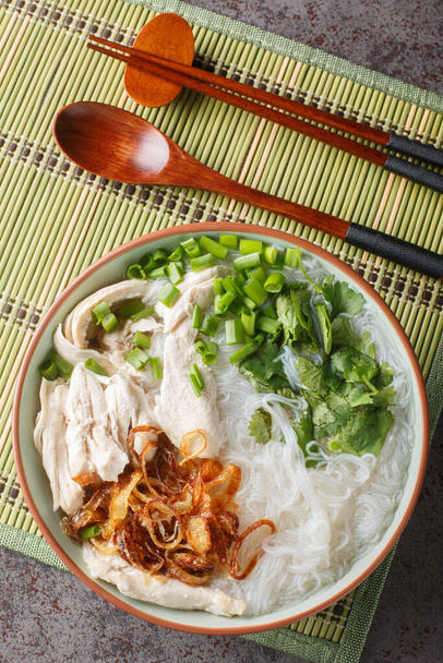 Soupe de poulet vietnamienne avec nouilles en verre Mien Ga gros plan sur le bol sur la table. Vue verticale du dessus depuis le dessus - Photo, image