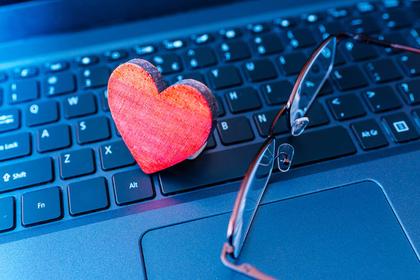 Remote senior date concept.distant video chat,red heart laptop keyboard with glasses.celebration, active leisure feeling alone.Close-up. - Photo, Image