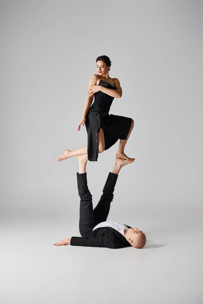 Dynamic duo of two acrobats performing balance act in a studio setting with grey background - Fotó, kép