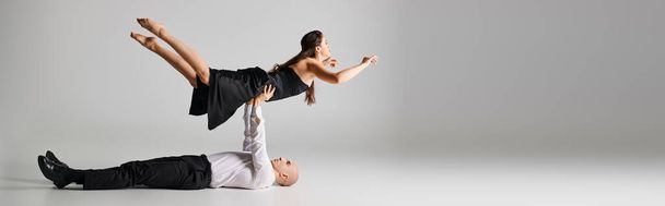 male dancer lying on the floor and lifting body of woman in dress during dance performance, banner - Photo, Image