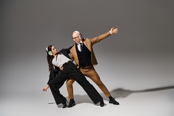 akrobaci w garniturach w słuchawkach bezprzewodowych tańczący w stylu biurowym, wyciągnięte ręce - Zdjęcie, obraz