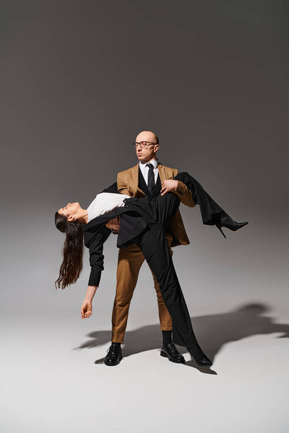 Elegant business couple in dramatic dance performance in studio setting on grey background - Photo, Image