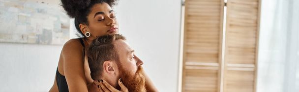 pancarta de diversa pareja, mujer afroamericana abrazando a su hombre tatuado en habitación luminosa - Foto, Imagen