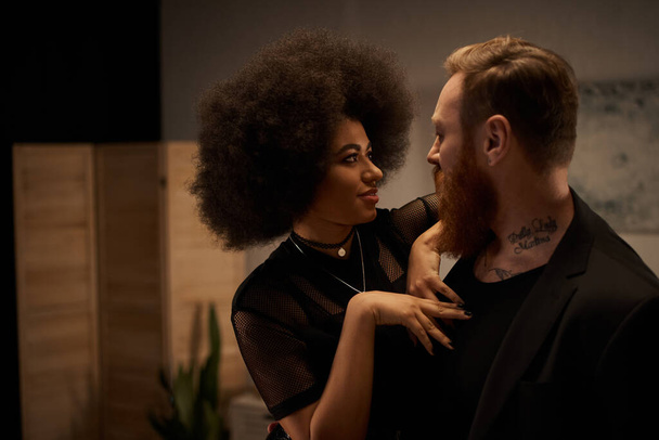 Kıvırcık saçlı Afro-Amerikalı kadın sakallı, dövmeli erkek arkadaşını baştan çıkarıyor. - Fotoğraf, Görsel