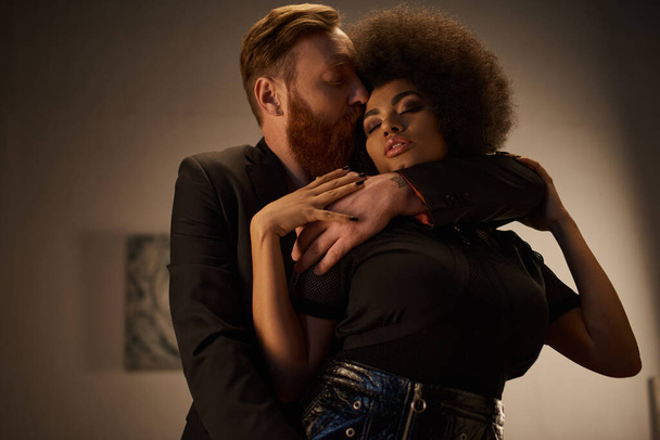 бородатый мужчина целует сексуальную африканскую американку с вьющимися волосами, интимный момент сексуальной пары - Фото, изображение