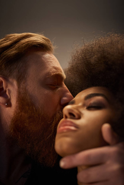 γενειοφόρος άντρας φιλάει σέξι αφροαμερικανή γυναίκα με σγουρά μαλλιά, οικεία στιγμή καυτού ζευγαριού - Φωτογραφία, εικόνα