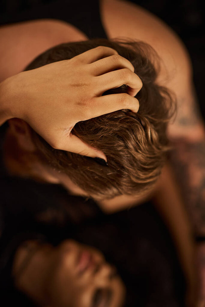 вид зверху на жінку, що тягне волосся рудого чоловіка під час нічної пристрасті в спальні, любові та бажанні - Фото, зображення