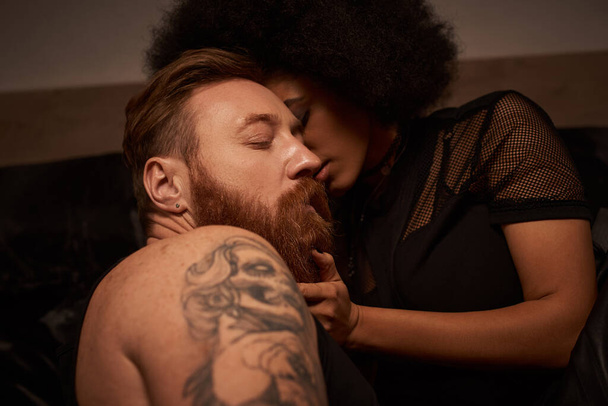 african american woman touching face of bearded man with tattoos while seducing him - Foto, Bild