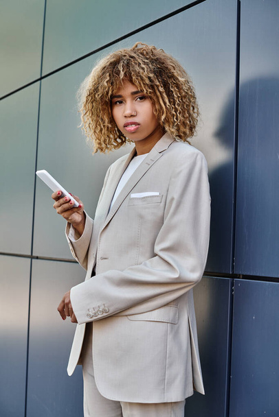 giovane e trafitto afroamericana donna d'affari con i capelli ricci utilizzando il suo smartphone all'aperto - Foto, immagini