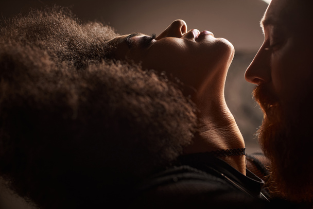 portrait of african american woman with curly hair seducing bearded man with red hair, sexy couple - Photo, Image