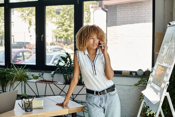 кучерявий і пустотливий афроамериканська бізнес-леді має телефонний дзвінок в сонячному світлі сучасний офіс - Фото, зображення