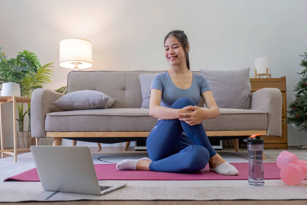 Young Asian sporty fitness woman coach do practice video online training yoga laptop in living room at home. - Photo, Image